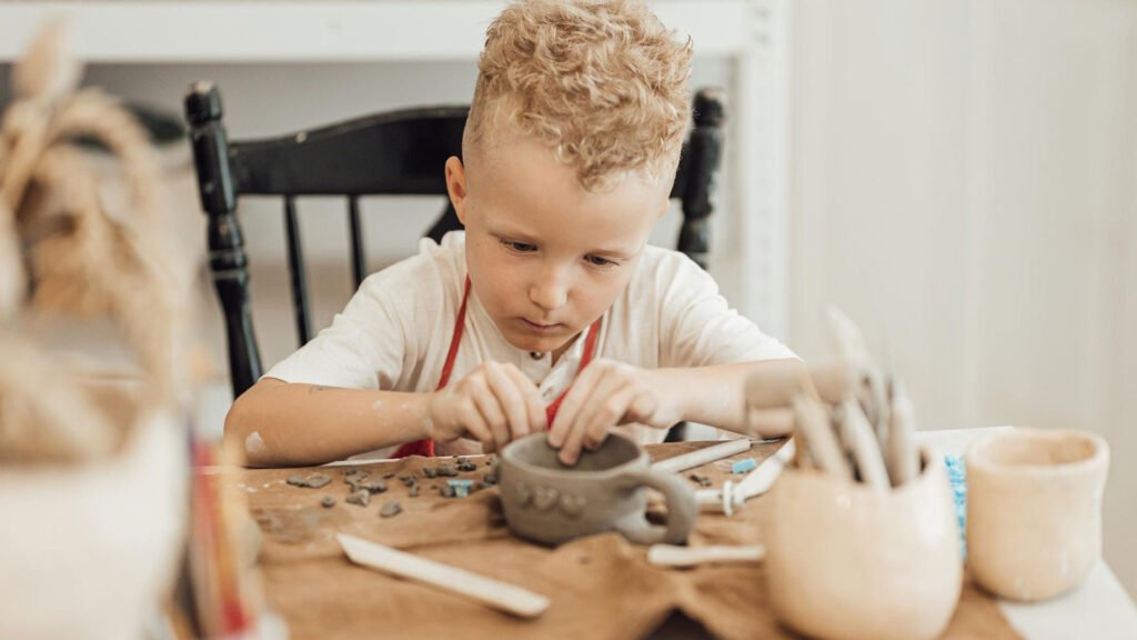 a boy crafting a cup with clay